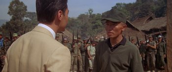 Movie still from “Year of the Dragon” (1985), directed by Michael Cimino – Two men are standing in front of a group of soldiers; Medium shot, Over the shoulder angle