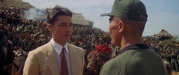 Movie still from “Year of the Dragon” (1985), directed by Michael Cimino – A man in a tan suit talking to another man in a green hat; Medium shot, Over the shoulder angle