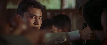 Movie still from “Year of the Dragon” (1985), directed by Michael Cimino – A person sitting in front of a window; Close Up shot, Over the shoulder angle