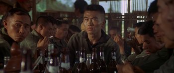 Movie still from “Year of the Dragon” (1985), directed by Michael Cimino – A man sitting at a table in front of several beer bottles; Close Up shot, Over the shoulder angle
