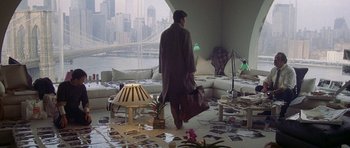 Movie still from “Year of the Dragon” (1985), directed by Michael Cimino – A man walking across a living room floor with a bag; Wide shot, High angle