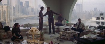 Movie still from “Year of the Dragon” (1985), directed by Michael Cimino – Two people standing in a living room talking to each other; Wide shot, High angle