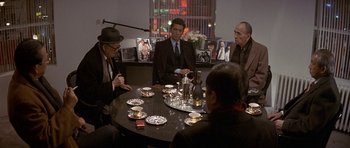 Movie still from “Year of the Dragon” (1985), directed by Michael Cimino – A group of men sitting around a round table; Wide shot, High angle