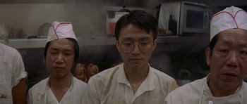 Movie still from “Year of the Dragon” (1985), directed by Michael Cimino – A man with glasses is looking at the camera; Close Up shot, High angle