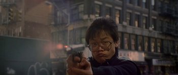 Movie still from “Year of the Dragon” (1985), directed by Michael Cimino – A man with glasses is holding a gun in his hand; Close Up shot, Low angle
