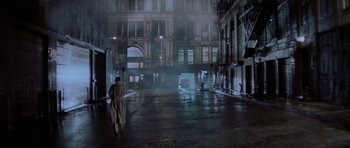 Movie still from “Year of the Dragon” (1985), directed by Michael Cimino – A man walking down a street in a dark city at night; Extreme Wide shot, High angle