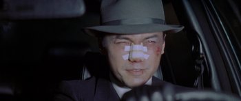 Movie still from “Year of the Dragon” (1985), directed by Michael Cimino – A man with bandages all over his face; Close Up shot, Low angle