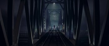 Movie still from “Year of the Dragon” (1985), directed by Michael Cimino – A man standing on a train track in a dark place; Extreme Wide shot, High angle