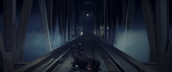 Movie still from “Year of the Dragon” (1985), directed by Michael Cimino – A man laying on the floor of a train tunnel; Wide shot, Overhead angle