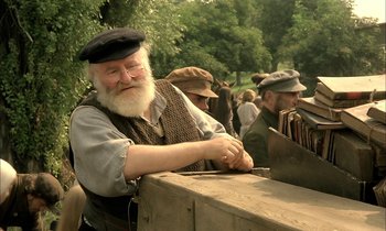 Movie still from “Yentl” (1983), directed by Barbra Streisand – An old man with a long white beard cutting something with a knife; Medium shot, Low angle