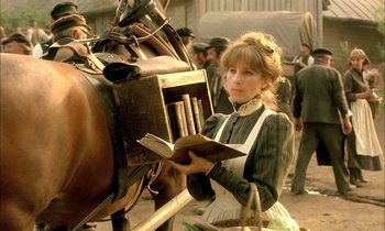 Movie still from “Yentl” (1983), directed by Barbra Streisand – A young woman reading a book while standing next to a horse; Medium shot, Low angle