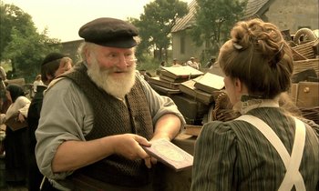 Movie still from “Yentl” (1983), directed by Barbra Streisand – An old man and a young girl are exchanging cards; Medium shot, Over the shoulder angle