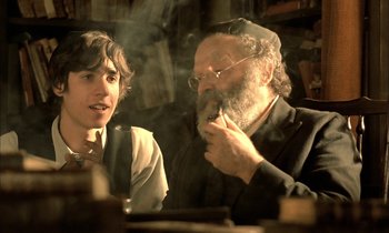 Movie still from “Yentl” (1983), directed by Barbra Streisand – A man and a woman sitting at a table; Medium shot, Over the shoulder angle