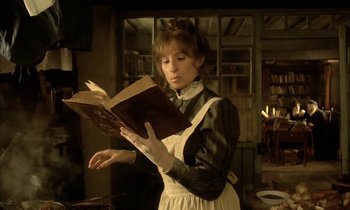 Movie still from “Yentl” (1983), directed by Barbra Streisand – A woman dressed as a maid reading a book; Medium shot, Low angle