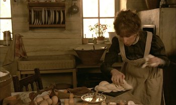 Movie still from “Yentl” (1983), directed by Barbra Streisand – A woman in an old - fashioned kitchen preparing food; Medium shot, High angle