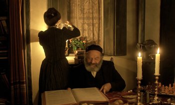 Movie still from “Yentl” (1983), directed by Barbra Streisand – An old man sitting at a table in front of an open book; Medium shot, Over the shoulder angle