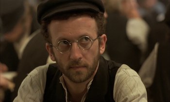 Movie still from “Yentl” (1983), directed by Barbra Streisand – A person wearing glasses and a hat; Close Up shot, Over the shoulder angle
