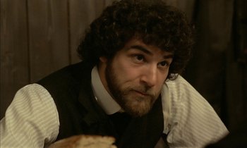 Movie still from “Yentl” (1983), directed by Barbra Streisand – A man with curly hair wearing a vest and a tie; Close Up shot, Over the shoulder angle