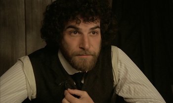 Movie still from “Yentl” (1983), directed by Barbra Streisand – A man with curly hair wearing a vest and tie; Close Up shot, High angle