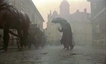 Movie still from “Yentl” (1983), directed by Barbra Streisand – A man holding an umbrella walking down a street; Wide shot, Low angle