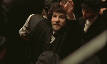 Movie still from “Yentl” (1983), directed by Barbra Streisand – A man with a beard and a hat is smiling for the camera; Medium shot, Low angle