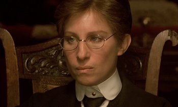 Movie still from “Yentl” (1983), directed by Barbra Streisand – A man in a suit and tie wearing glasses; Close Up shot, High angle