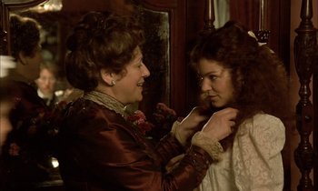 Movie still from “Yentl” (1983), directed by Barbra Streisand – A woman adjusting a young girl's collar; Medium shot, Over the shoulder angle