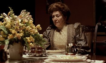 Movie still from “Yentl” (1983), directed by Barbra Streisand – An older woman sitting at a dinner table; Medium shot, Low angle