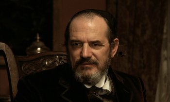 Movie still from “Yentl” (1983), directed by Barbra Streisand – An older man with a beard and a mustache wearing a hat; Close Up shot, Low angle