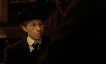 Movie still from “Yentl” (1983), directed by Barbra Streisand – A man in a hat and glasses is looking at the camera; Close Up shot, Over the shoulder angle