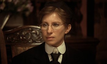 Movie still from “Yentl” (1983), directed by Barbra Streisand – A woman wearing glasses and a suit and tie; Close Up shot, High angle