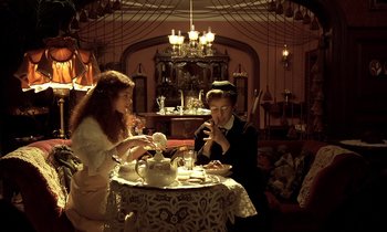 Movie still from “Yentl” (1983), directed by Barbra Streisand – Two people sitting at a table with a tea set; Wide shot, High angle
