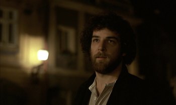 Movie still from “Yentl” (1983), directed by Barbra Streisand – A man with curly hair and a white shirt; Close Up shot, Low angle