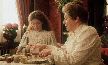 Movie still from “Yentl” (1983), directed by Barbra Streisand – A woman and a girl sitting at a table with a cake; Medium shot, High angle
