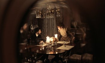 Movie still from “Yentl” (1983), directed by Barbra Streisand – Two people sitting at a table with candles in a room; Wide shot, High angle