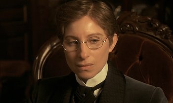 Movie still from “Yentl” (1983), directed by Barbra Streisand – A man in a suit and tie wearing glasses; Close Up shot, High angle