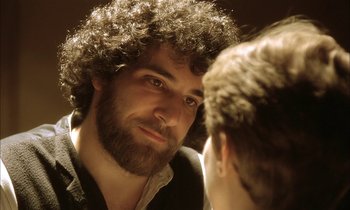 Movie still from “Yentl” (1983), directed by Barbra Streisand – A bearded man looking into a mirror while standing next to another man; Close Up shot, Over the shoulder angle