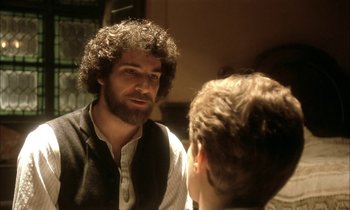 Movie still from “Yentl” (1983), directed by Barbra Streisand – A man with curly hair talking to another man in front of a mirror; Close Up shot, Over the shoulder angle