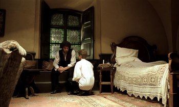 Movie still from “Yentl” (1983), directed by Barbra Streisand – A man and a boy sitting in a room next to each other; Wide shot, High angle