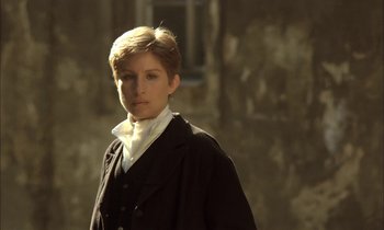 Movie still from “Yentl” (1983), directed by Barbra Streisand – A young man in a black jacket standing in front of an old building; Close Up shot, Over the shoulder angle