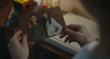 Movie still from “Yes, God, Yes” (2019), directed by Karen Maine – A woman holding a picture of a man and a woman; Close Up shot, Over the shoulder angle