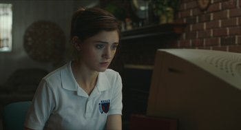 Movie still from “Yes, God, Yes” (2019), directed by Karen Maine – A girl in a white shirt is sitting in front of a computer; Close Up shot, Over the shoulder angle