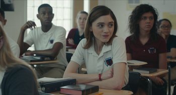 Movie still from “Yes, God, Yes” (2019), directed by Karen Maine – A girl sitting at a desk in front of other students; Medium shot, Over the shoulder angle