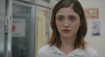 Movie still from “Yes, God, Yes” (2019), directed by Karen Maine – A woman with a white shirt and a black headband; Close Up shot, Over the shoulder angle