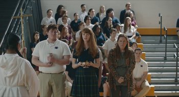 Movie still from “Yes, God, Yes” (2019), directed by Karen Maine – A group of people standing in front of a group of people; Wide shot, Over the shoulder angle