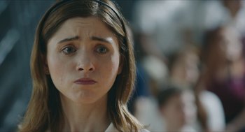 Movie still from “Yes, God, Yes” (2019), directed by Karen Maine – A young girl is looking sad while standing in front of a group of people; Close Up shot, Over the shoulder angle