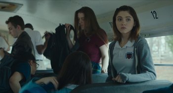 Movie still from “Yes, God, Yes” (2019), directed by Karen Maine – A group of young people riding on a bus together; Medium shot, Over the shoulder angle