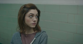 Movie still from “Yes, God, Yes” (2019), directed by Karen Maine – A woman with a brown hair and blue eyes looking to her left; Close Up shot, Over the shoulder angle