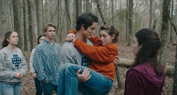 Movie still from “Yes, God, Yes” (2019), directed by Karen Maine – A group of people standing in the woods with trees in the background; Medium shot, Over the shoulder angle