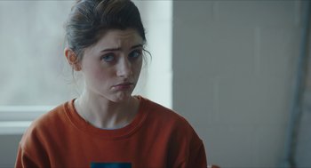 Movie still from “Yes, God, Yes” (2019), directed by Karen Maine – A woman in an orange shirt is looking sad; Close Up shot, Over the shoulder angle